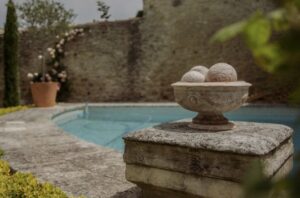 Coupelle en pierre au bord d'une piscine avec des boules parfumées ampholia